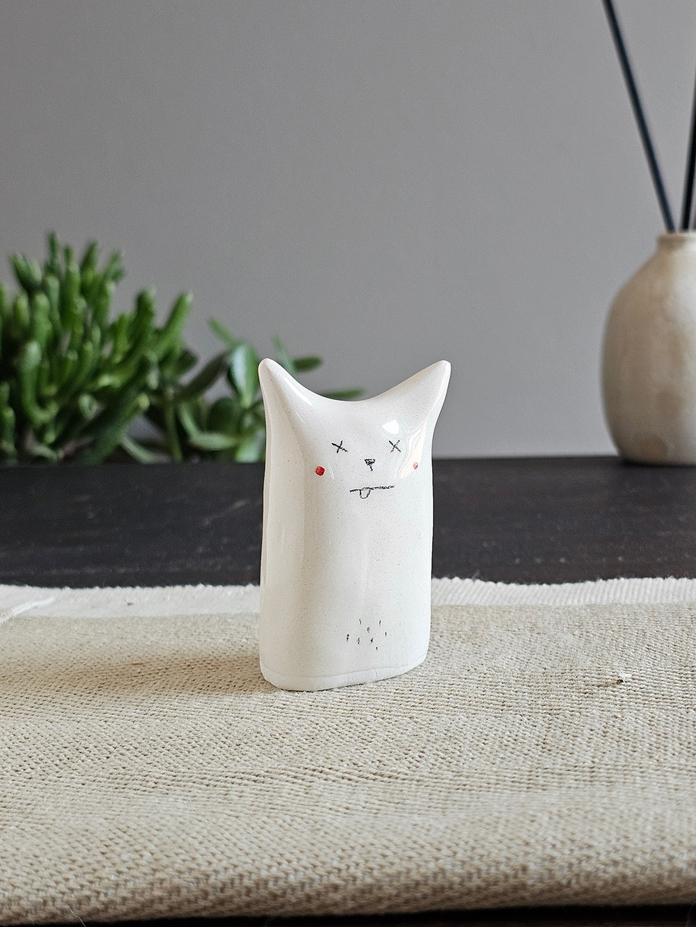 Scultura in ceramica bianca in una pozza, con due strisce azzurre che scendono