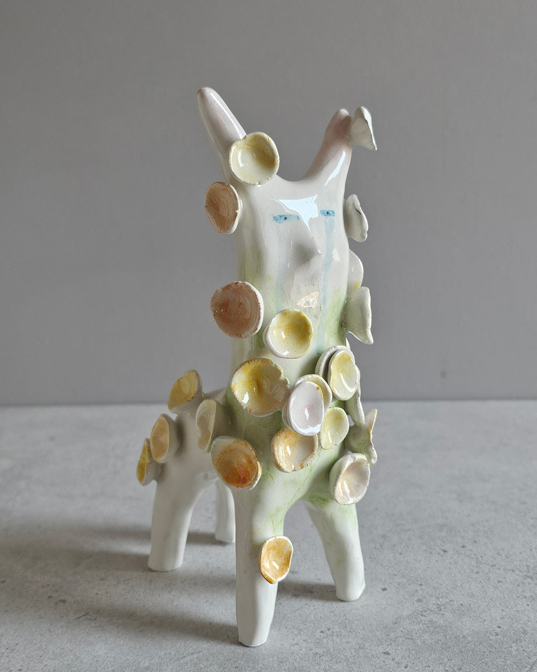 Scultura in ceramica di una figura che fiorisce, decorata a mano