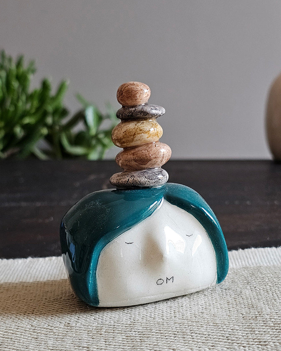 Testina in ceramica bianca con cinque sassi zen impilati in testa, fatta a mano