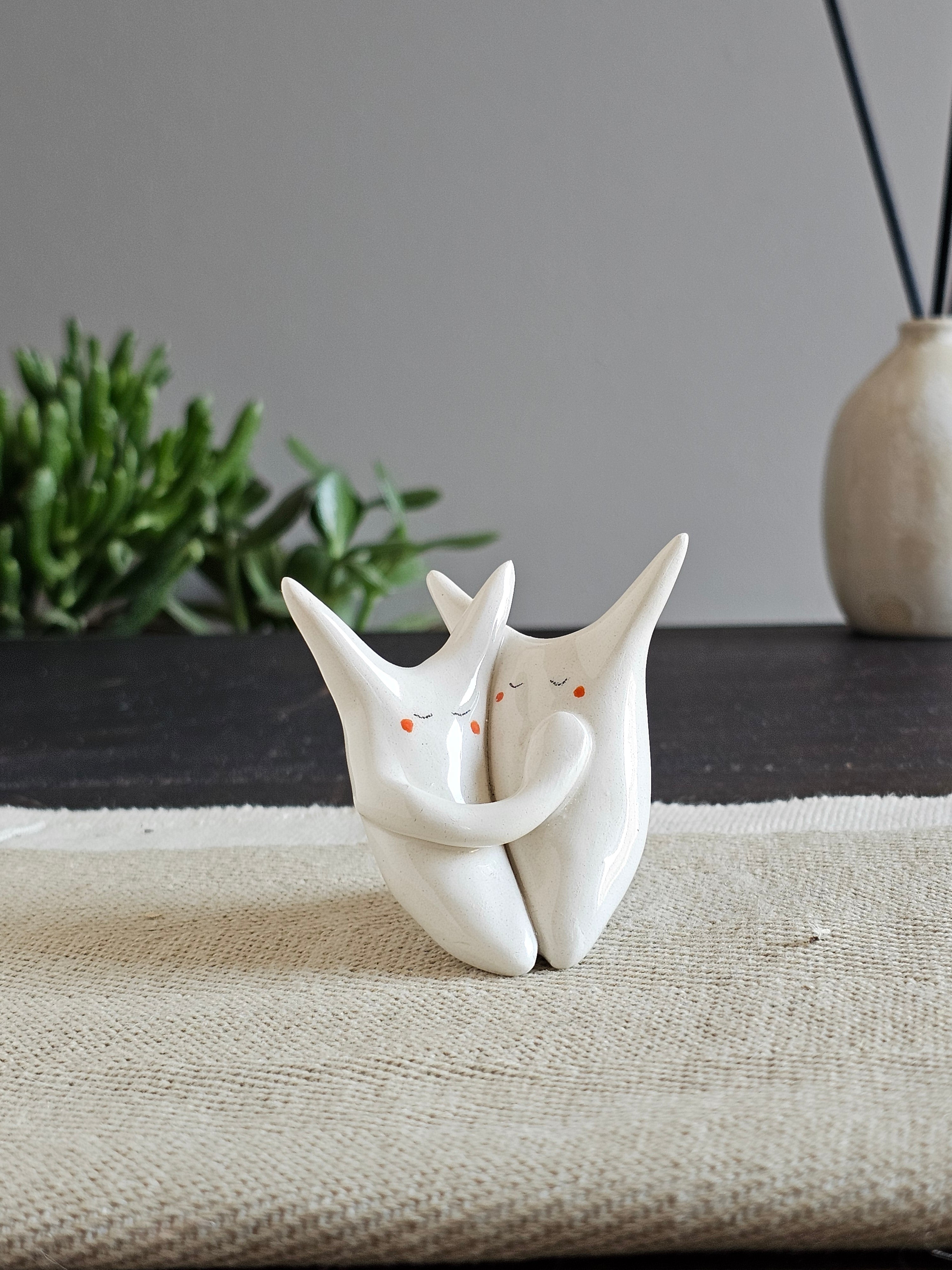 Due animali in ceramica bianca fusi insieme in un abbraccio sciolto