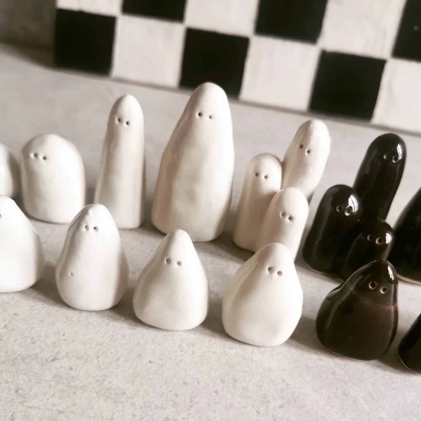 Scacchiera in ceramica con pezzi a forma di fantasmi, modellati a mano uno per uno