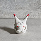 Gatto in ceramica bianca con espressione sorridente, dipinto a mano