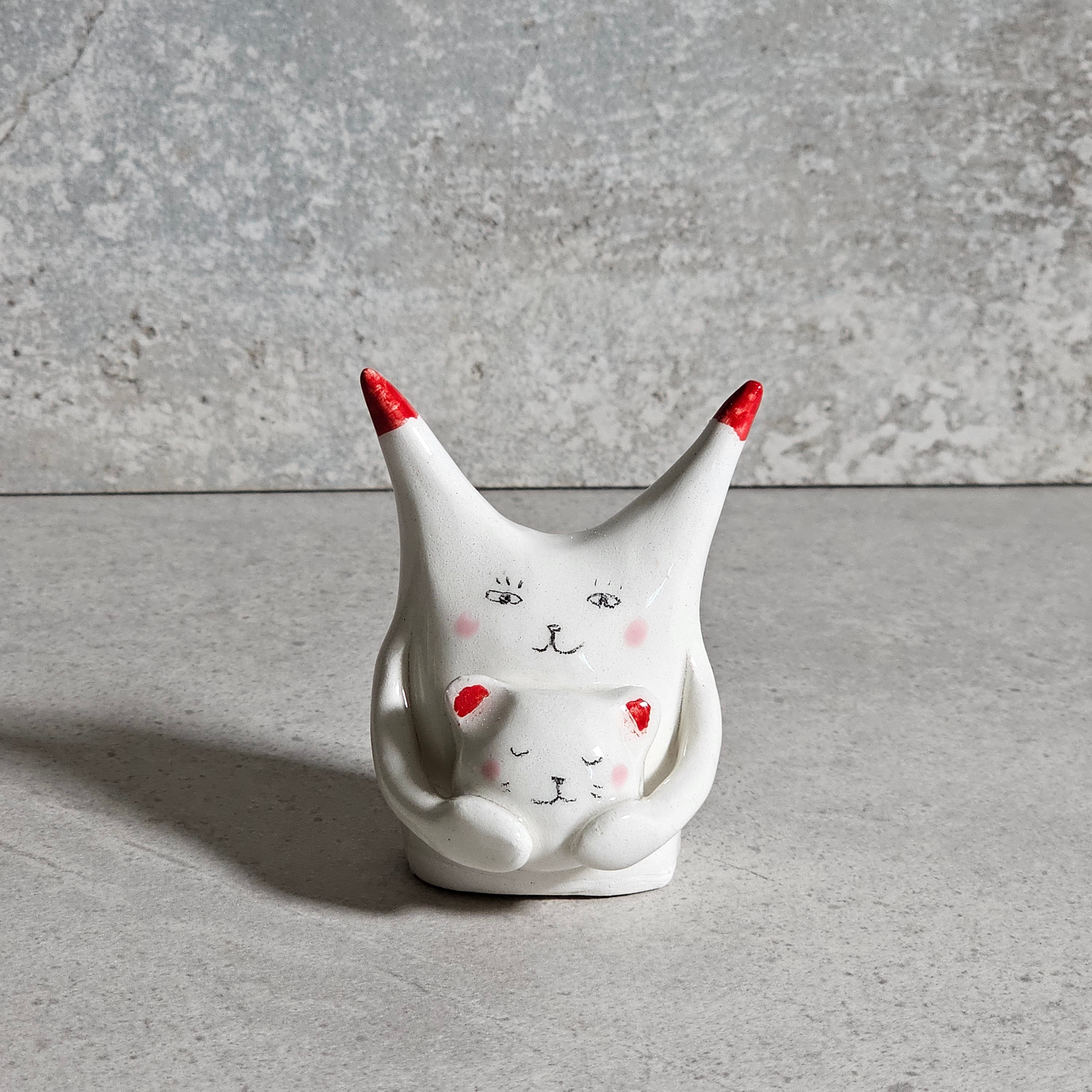 Gatto in ceramica bianca con espressione sorridente, dipinto a mano