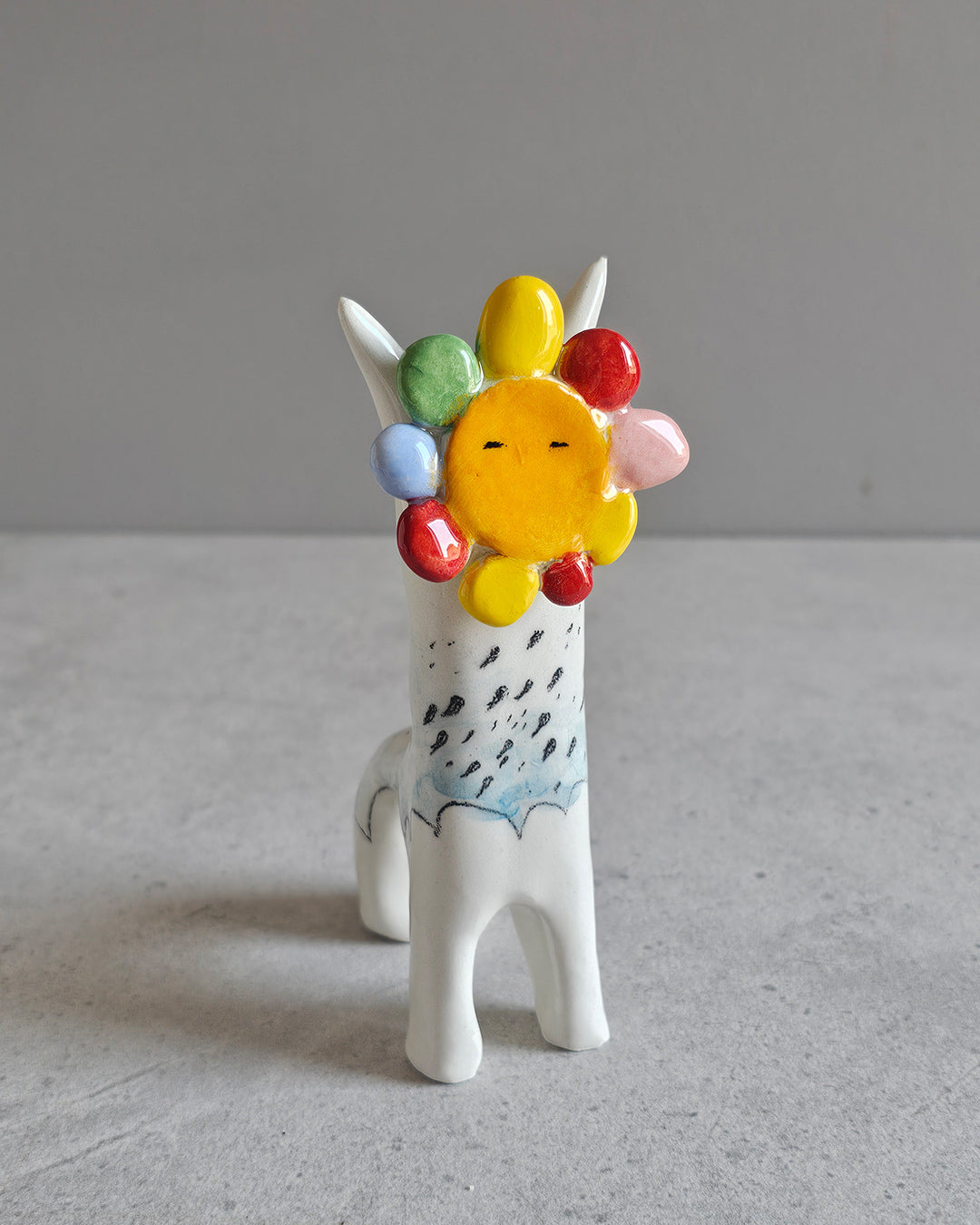 Scultura in ceramica di un sole che fa piovere al contrario, decorata a mano