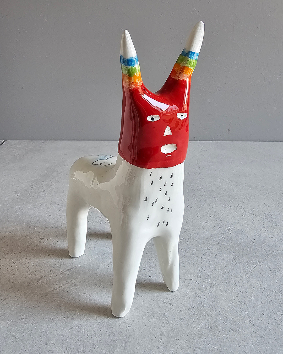 Scultura in ceramica di una figura dall'espressione stupefatta, decorata a mano