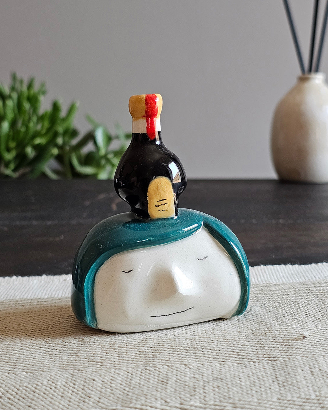 Testina in ceramica bianca con una boccetta di aceto balsamico appoggiata in testa