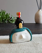 Testina in ceramica bianca con una boccetta di aceto balsamico appoggiata in testa