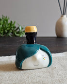 Testina in ceramica bianca con una pinta di birra scura appoggiata in testa