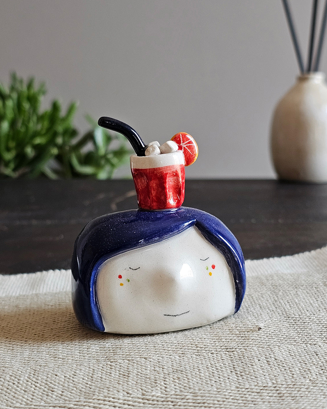 Testina in ceramica bianca con un Negroni rosso appoggiato in testa, fatta a mano