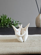 Due animali in ceramica bianca fusi insieme in un abbraccio sciolto