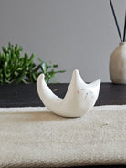 Animale in ceramica bianca disteso in avanti con la coda alzata