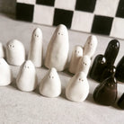 Scacchiera in ceramica con pezzi a forma di fantasmi, modellati a mano uno per uno