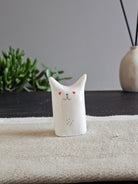 Scultura in ceramica bianca con occhi a cuore dipinti a mano