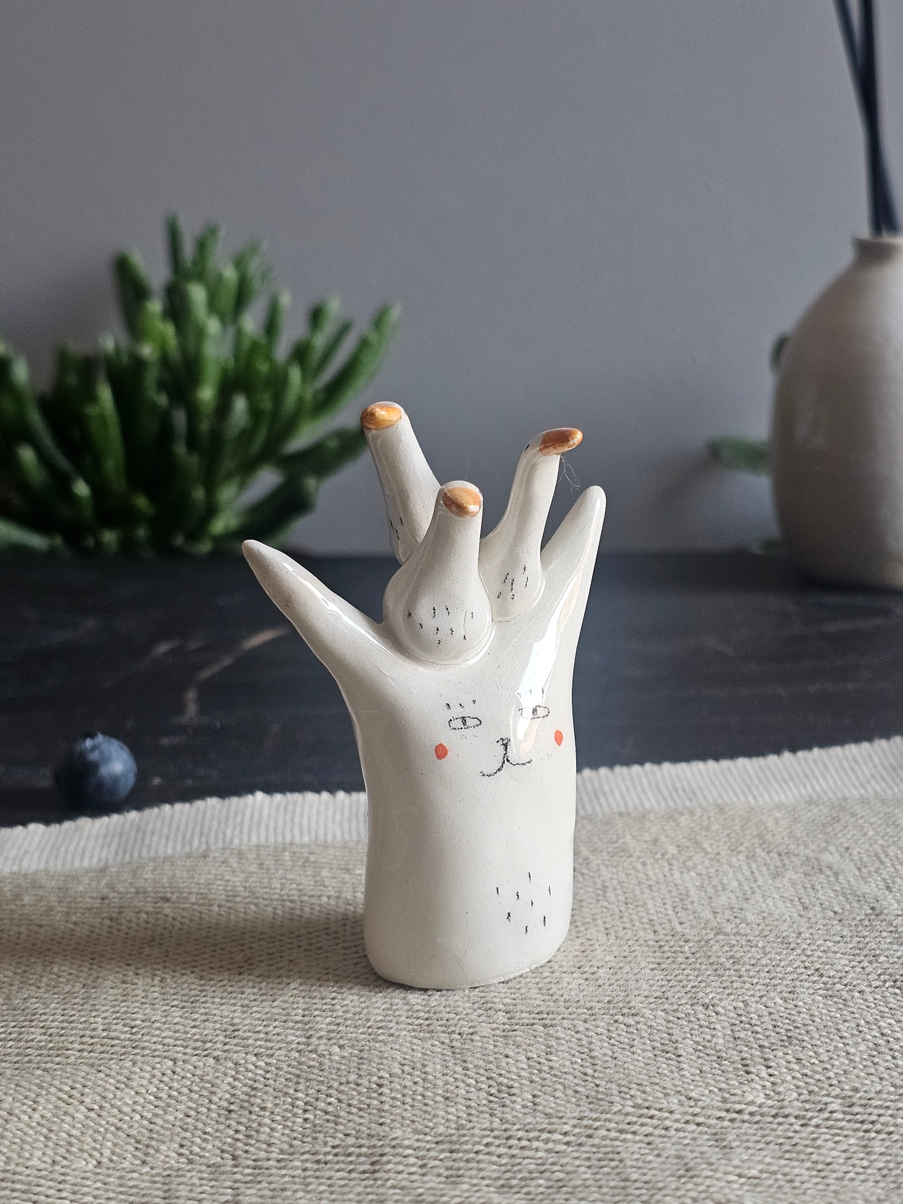 Scultura in ceramica bianca con un gruppo di oche modellate sulla testa