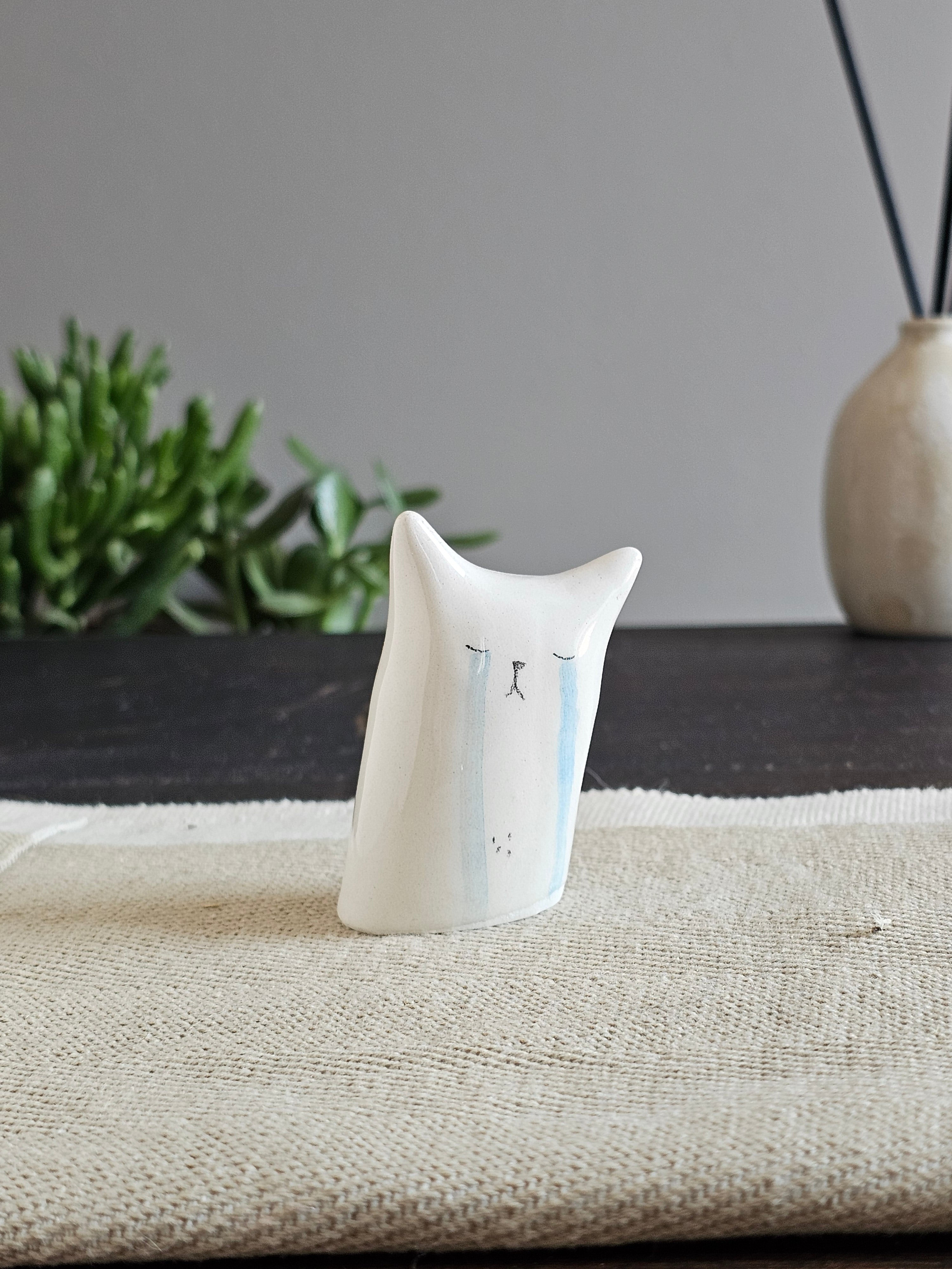 Scultura in ceramica bianca inclinata, con lacrime azzurre dipinte a mano