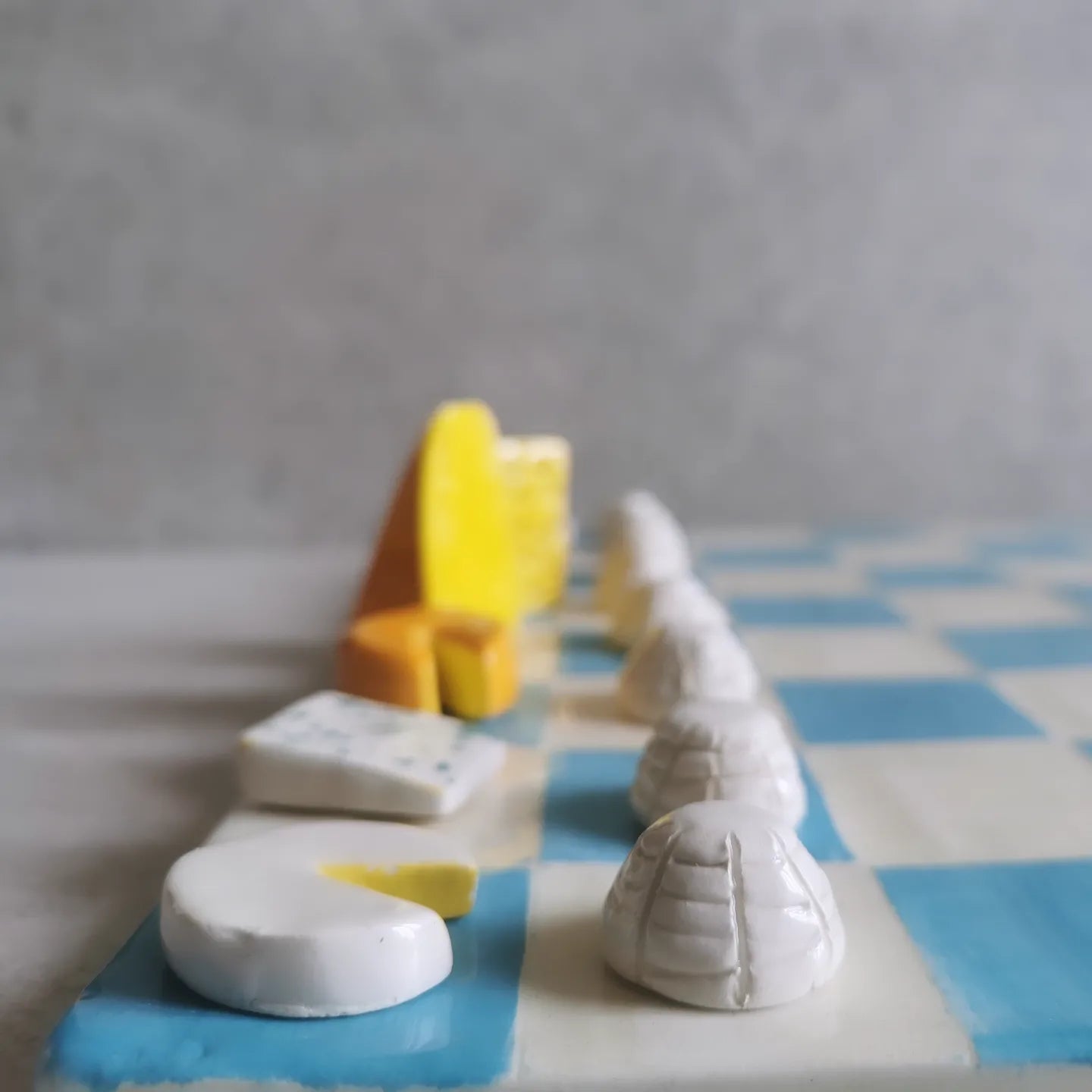 Scacchiera in ceramica con pezzi a forma di formaggi, modellati a mano uno per uno