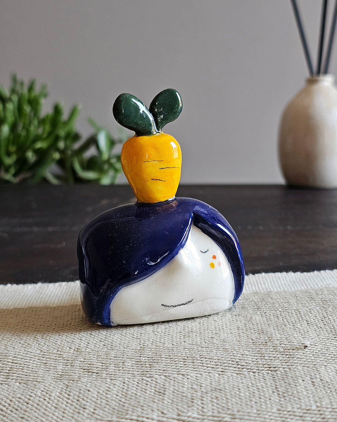 Testina in ceramica bianca con una carota gialla e ciuffo verde in testa