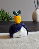 Testina in ceramica bianca con una carota gialla e ciuffo verde in testa
