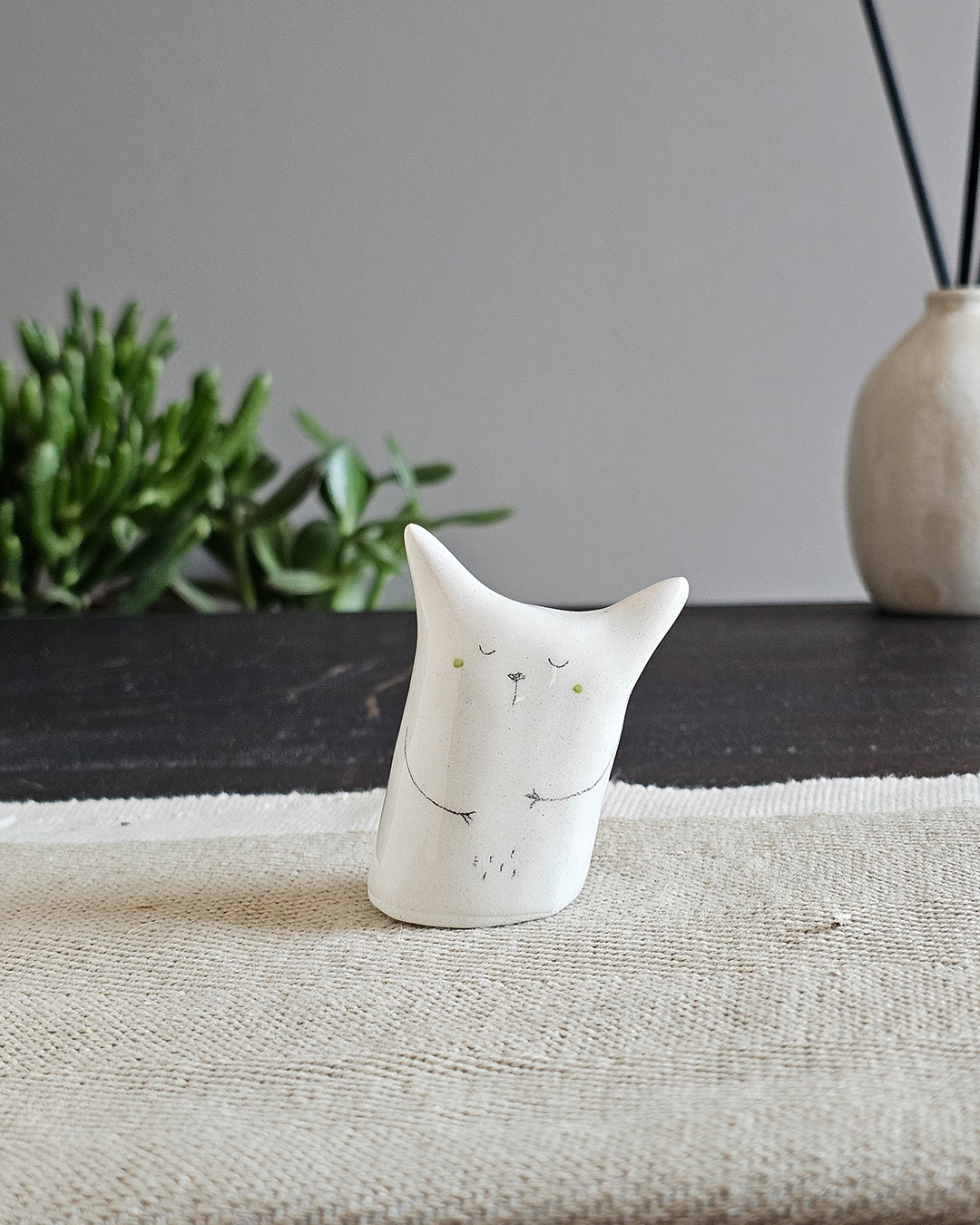 Scultura in ceramica bianca con gli occhi a croce, come svenuta