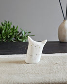 Scultura in ceramica bianca con gli occhi a croce, come svenuta