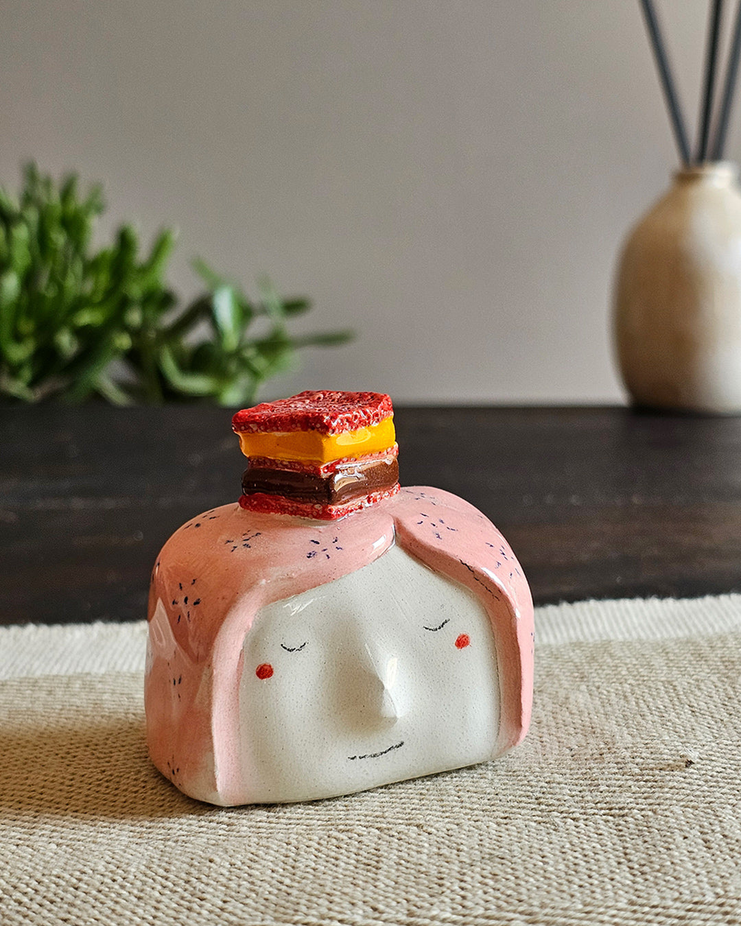 Testina in ceramica bianca con una fetta di zuppa inglese appoggiata in testa